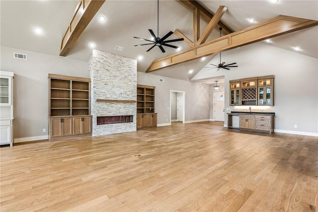 unfurnished living room featuring beamed ceiling, baseboards, a stone fireplace, ceiling fan, and high vaulted ceiling