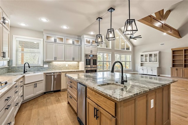 kitchen with appliances with stainless steel finishes, a sink, plenty of natural light, a ceiling fan, and light wood-type flooring