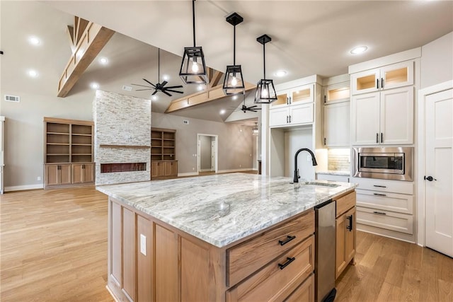 kitchen featuring a sink, light wood-style floors, a ceiling fan, stainless steel microwave, and visible vents
