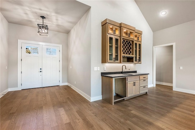entrance foyer featuring indoor wet bar, baseboards, vaulted ceiling, and dark wood-type flooring