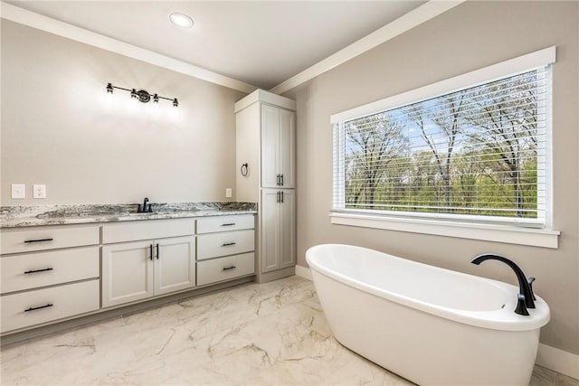 bathroom featuring vanity, crown molding, marble finish floor, a freestanding tub, and baseboards