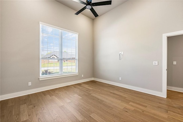 unfurnished room featuring vaulted ceiling, baseboards, a ceiling fan, and wood finished floors