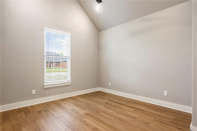 unfurnished room featuring baseboards, vaulted ceiling, and light wood finished floors