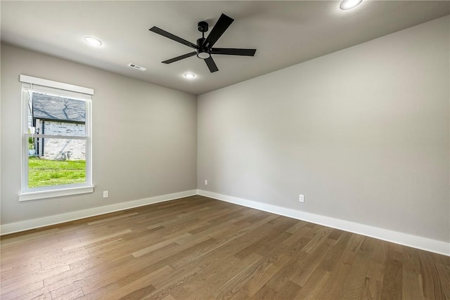 spare room featuring baseboards, ceiling fan, wood finished floors, and visible vents