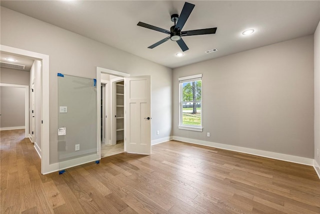 unfurnished bedroom featuring baseboards, visible vents, a walk in closet, and light wood-style floors