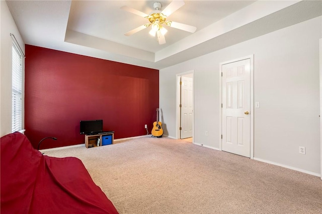 carpeted bedroom with baseboards, a ceiling fan, and a tray ceiling