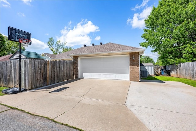 garage with concrete driveway and fence