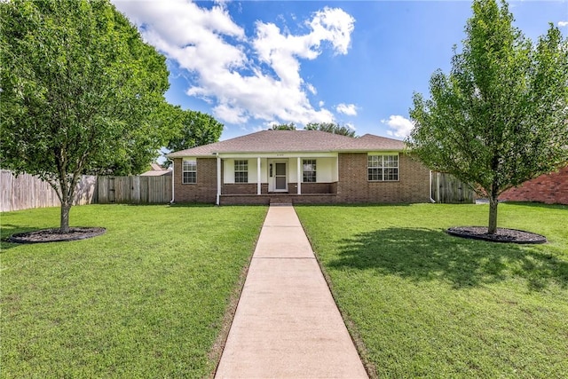 view of front of property with covered porch, brick siding, fence, and a front yard