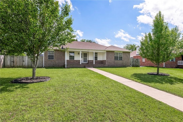 ranch-style home with brick siding, a front lawn, fence, and covered porch