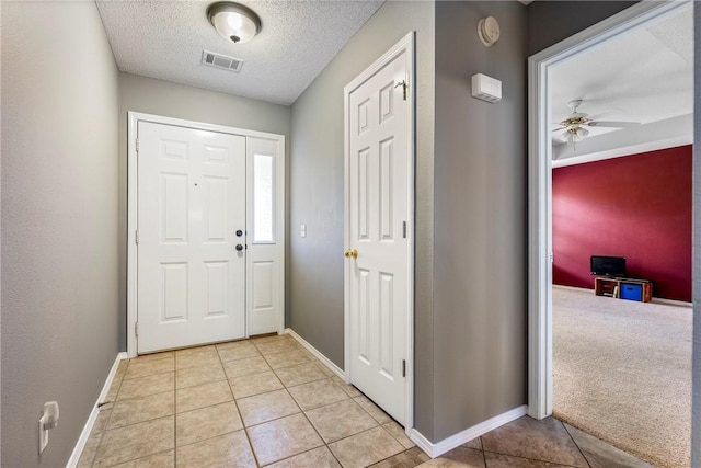 entryway featuring visible vents, baseboards, a textured ceiling, a ceiling fan, and light tile patterned floors