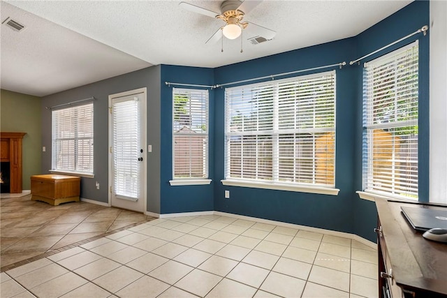 interior space featuring light tile patterned floors, a ceiling fan, a textured ceiling, and visible vents