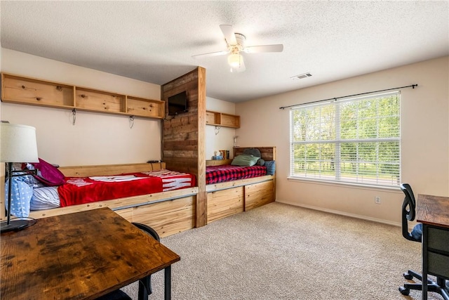carpeted bedroom with visible vents, a textured ceiling, ceiling fan, and baseboards