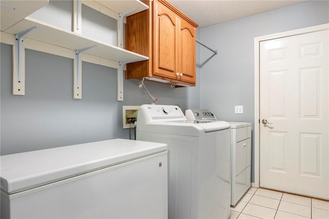 clothes washing area featuring light tile patterned flooring, independent washer and dryer, and cabinet space