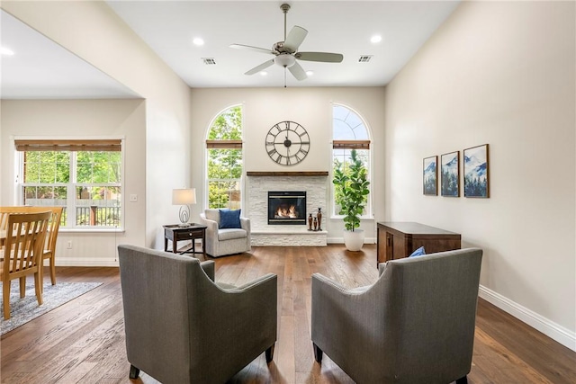 living area with wood finished floors, baseboards, ceiling fan, and a fireplace