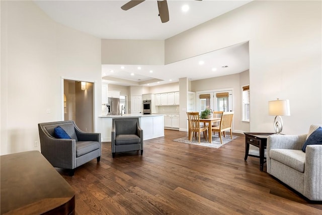 living room featuring a towering ceiling, dark wood-type flooring, a ceiling fan, and recessed lighting