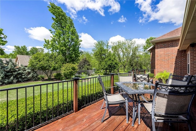 wooden deck featuring a lawn and outdoor dining area