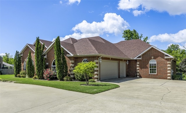 view of front of property with an attached garage, concrete driveway, a front yard, brick siding, and roof with shingles