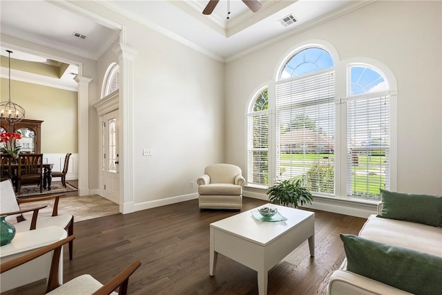 living room featuring crown molding, visible vents, and ceiling fan with notable chandelier
