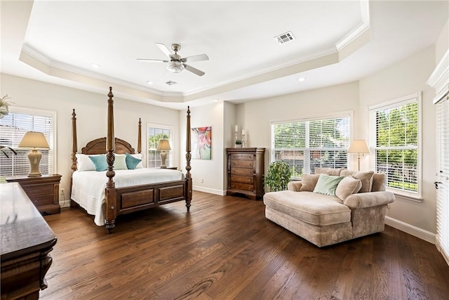 bedroom featuring dark wood-style flooring, ornamental molding, a tray ceiling, and visible vents