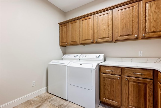 clothes washing area featuring washing machine and clothes dryer, cabinet space, and baseboards