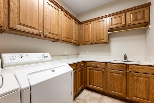 clothes washing area featuring a sink, cabinet space, and washing machine and dryer