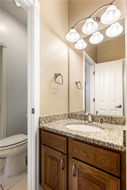 bathroom featuring toilet, tile patterned flooring, and vanity