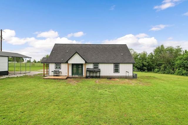 rear view of house featuring roof with shingles, central air condition unit, a lawn, and a wooden deck