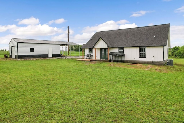 back of house with a lawn, an outdoor structure, french doors, and a shingled roof