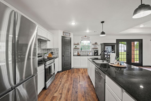 kitchen with decorative backsplash, appliances with stainless steel finishes, open shelves, dark wood finished floors, and a sink