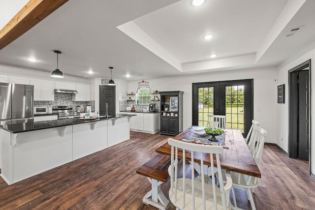 dining area featuring recessed lighting, french doors, a raised ceiling, and dark wood-type flooring