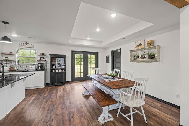 dining space with recessed lighting, a tray ceiling, and dark wood finished floors