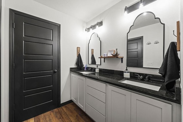 full bath with double vanity, a sink, and wood finished floors