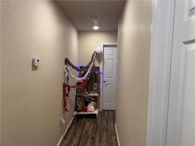 hallway with baseboards, a textured wall, and dark wood-style floors