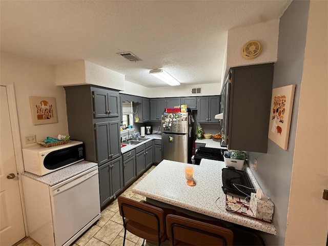 809 Walnut, Dardanelle, AR 72834 - kitchen featuring visible vents, freestanding refrigerator, a peninsula, gray cabinets, and a sink