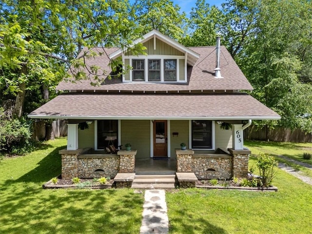 605 N Wright St, Siloam Springs, AR 72761 - view of front of home with a front lawn, fence, stone siding, roof with shingles, and a porch