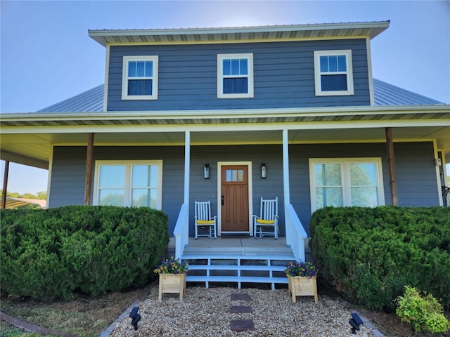 farmhouse-style home featuring a porch and metal roof