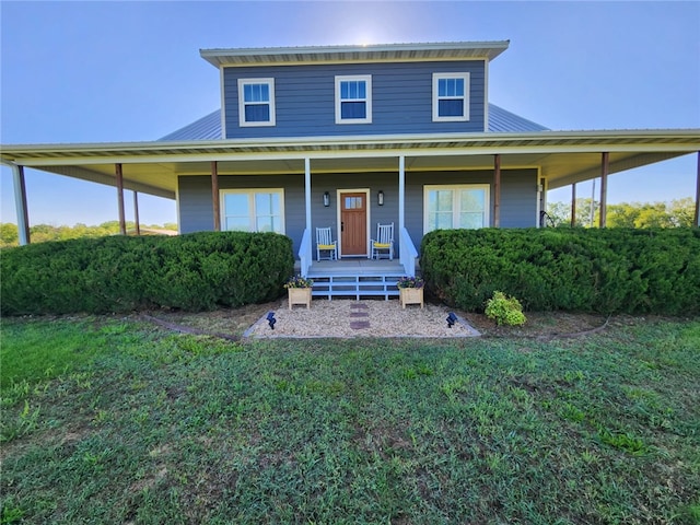 farmhouse with a porch, metal roof, and a front lawn
