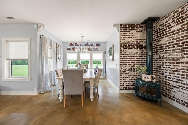 dining room featuring a wood stove, brick wall, concrete floors, baseboards, and visible vents