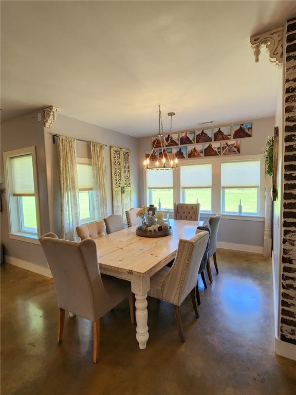 dining space with finished concrete flooring, baseboards, and a notable chandelier