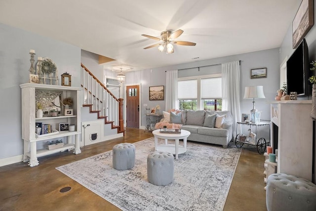 living room with ceiling fan, a fireplace, concrete flooring, baseboards, and stairs