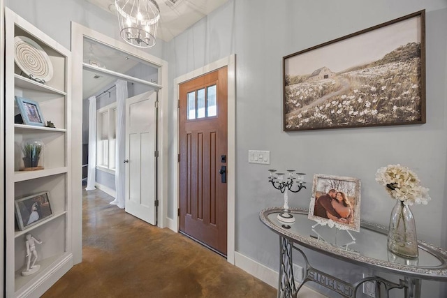 entrance foyer featuring baseboards, concrete floors, and a notable chandelier