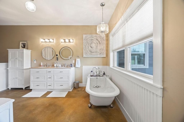 bathroom with double vanity, a freestanding tub, concrete flooring, a sink, and a notable chandelier
