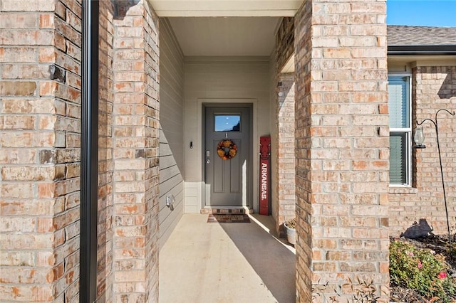 property entrance with roof with shingles and brick siding
