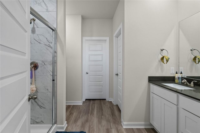 bathroom featuring vanity, baseboards, a shower stall, and wood finished floors