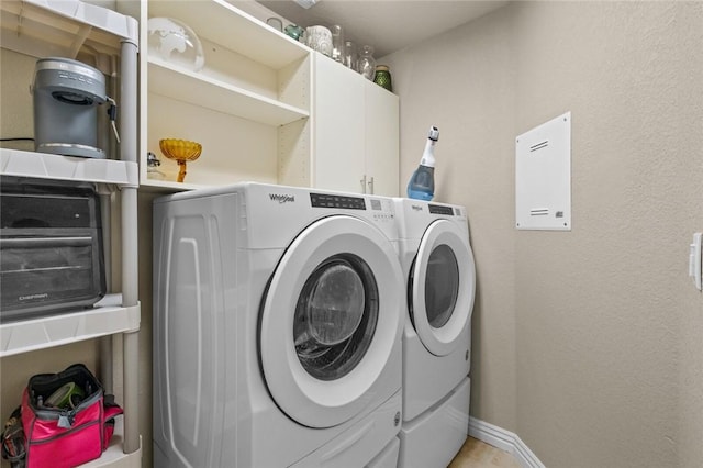 clothes washing area with separate washer and dryer and cabinet space
