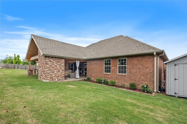 rear view of house featuring brick siding, roof with shingles, a storage shed, a patio area, and an outbuilding