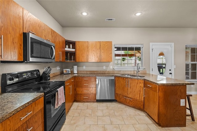 kitchen featuring stainless steel appliances, a sink, a peninsula, brown cabinetry, and recessed lighting