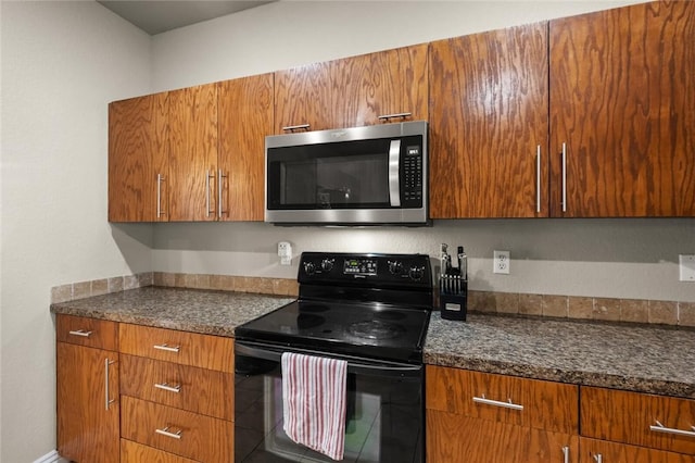 kitchen with stainless steel microwave, black range with electric cooktop, and brown cabinets