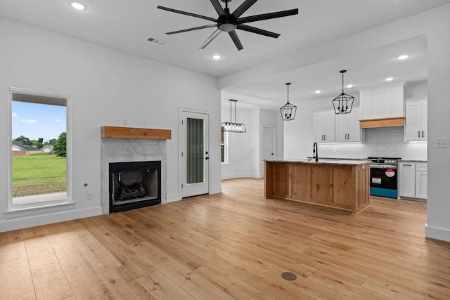 kitchen featuring open floor plan, light wood-style floors, visible vents, ceiling fan, and stainless steel range