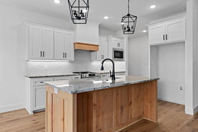 kitchen featuring a sink, light wood finished floors, tasteful backsplash, and appliances with stainless steel finishes
